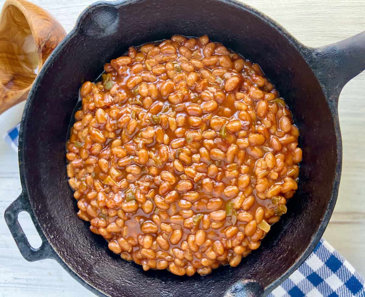 Southern baked beans in cast iron skillet on trivet.