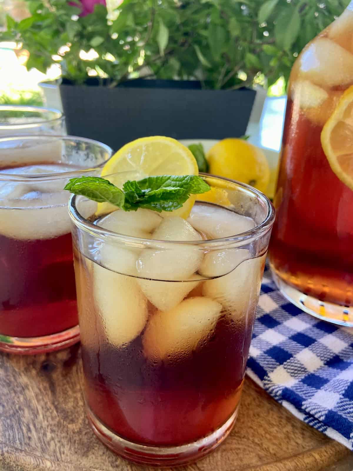 Close up glass of iced sweet tea with lemon slice and fresh mint sprig.