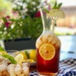 Iced sweet tea in a carafe with a lemon slice in the tea.