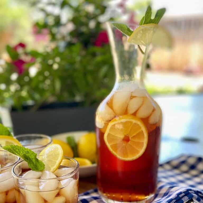 Iced sweet tea in a carafe with a lemon slice in the tea.