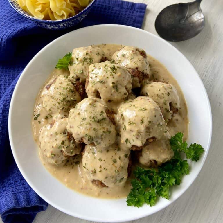 Swedish meatballs in gravy in white serving bowl.