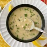 White bean soup on spoon in black bowl.