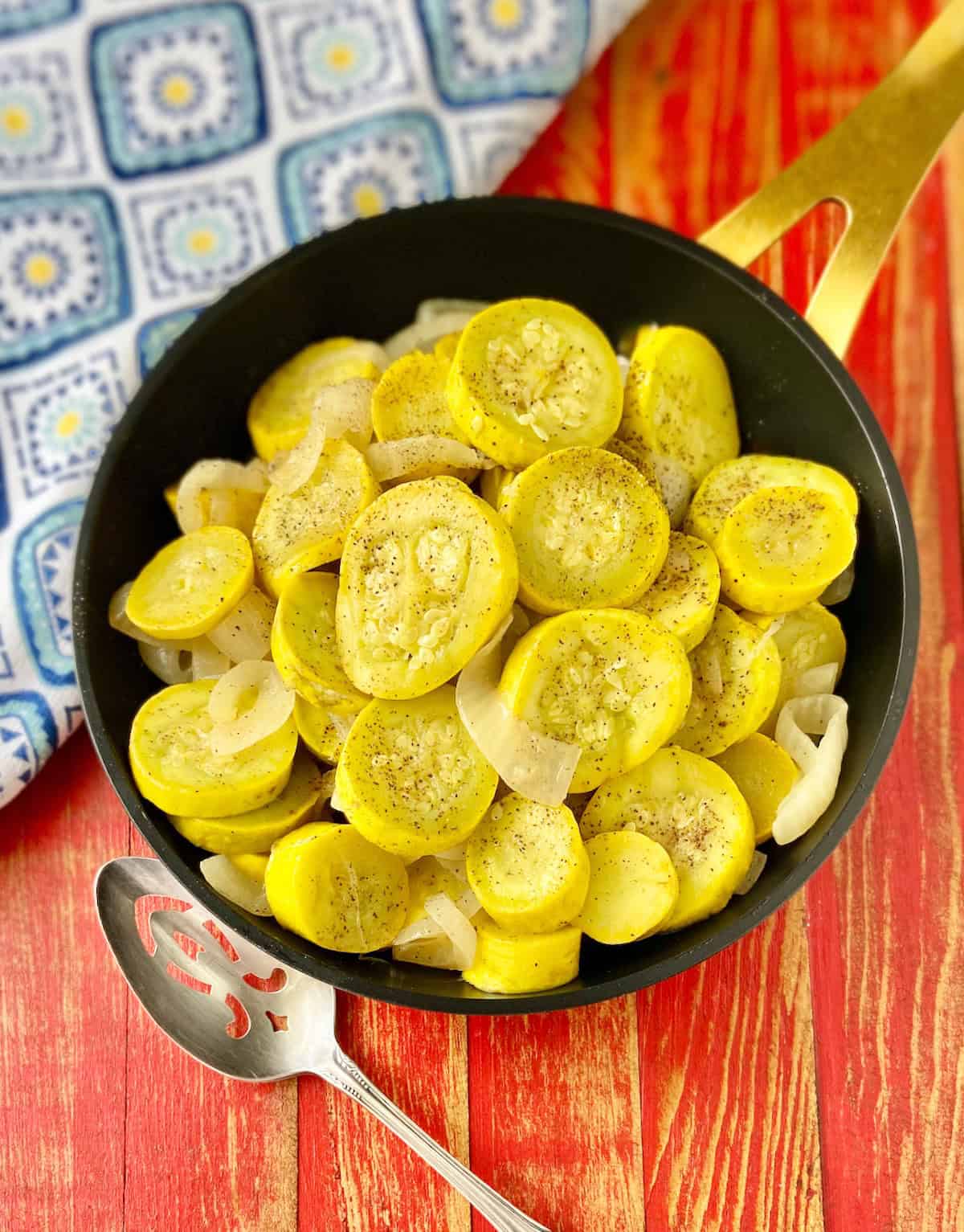 Sauteed yellow squash and onions in black skillet.