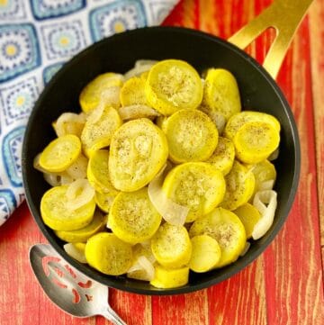 Sauteed yellow squash and onions in black skillet.