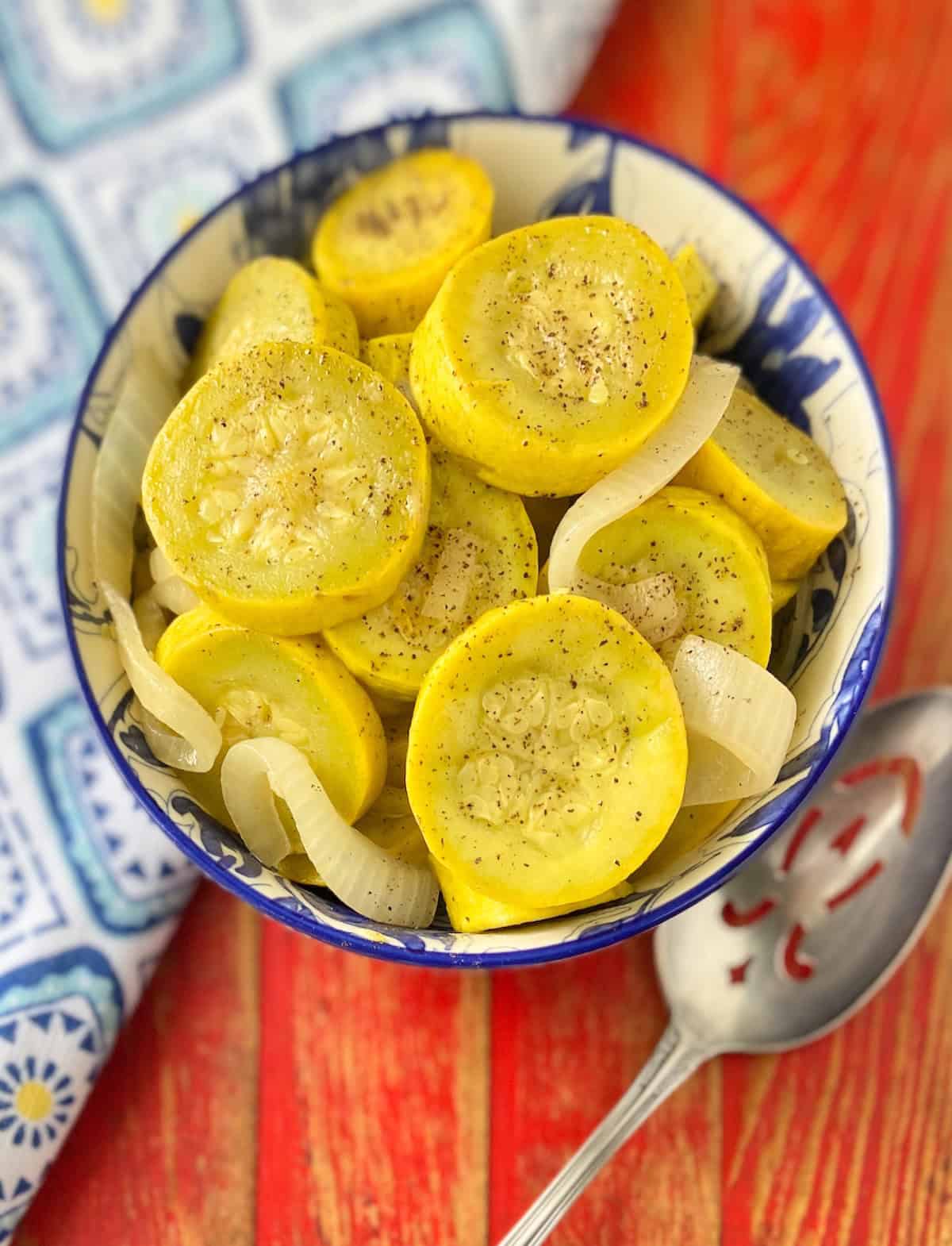 Close up image of sauteed yellow squash and onions in decorative blue and white serving bowl.