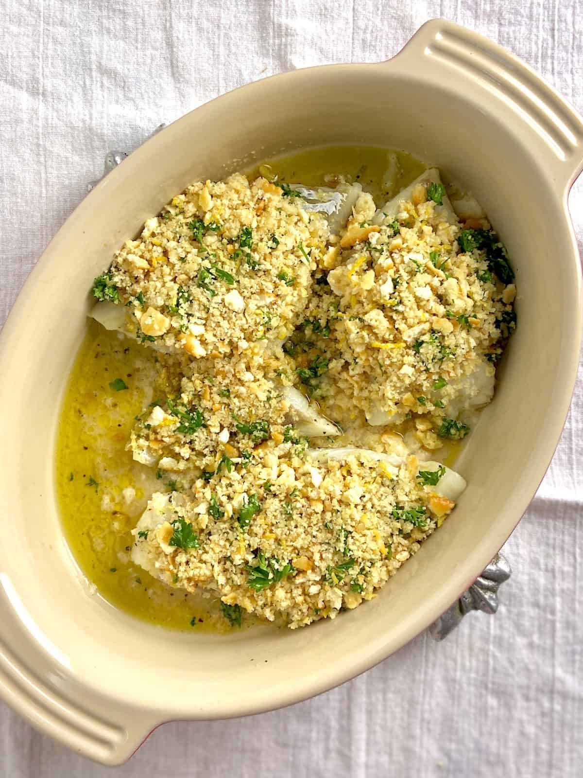Baked cod with breadcrumbs on top in baking dish.