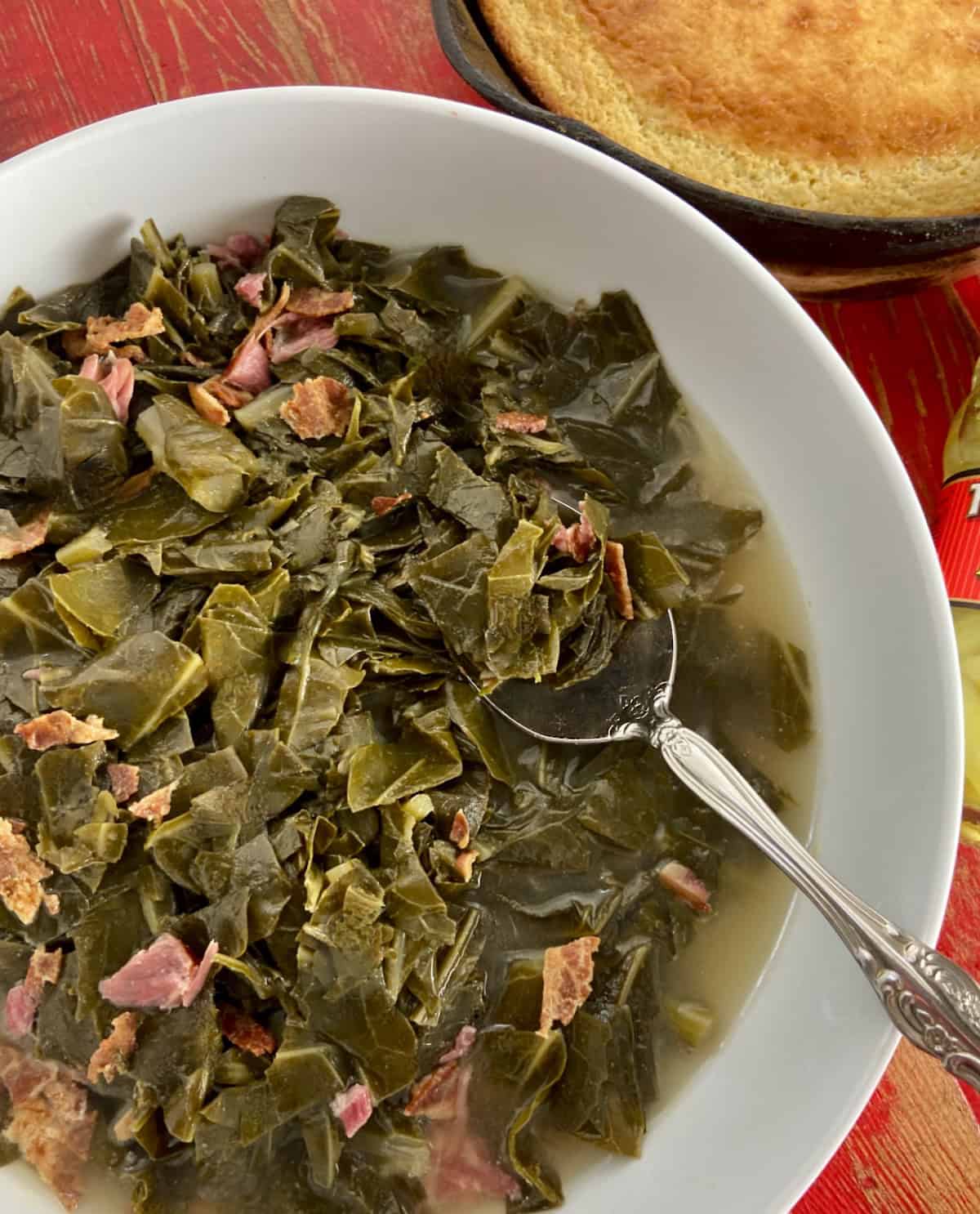 Southern collard greens in white bowl with serving spoon.