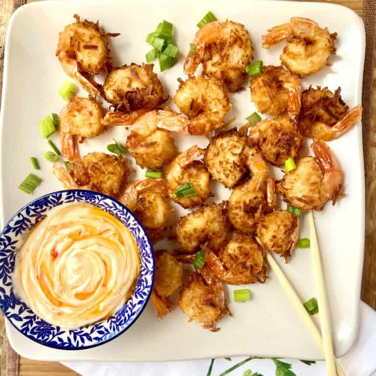 Coconut fried shrimp on serving platter with dipping sauce.