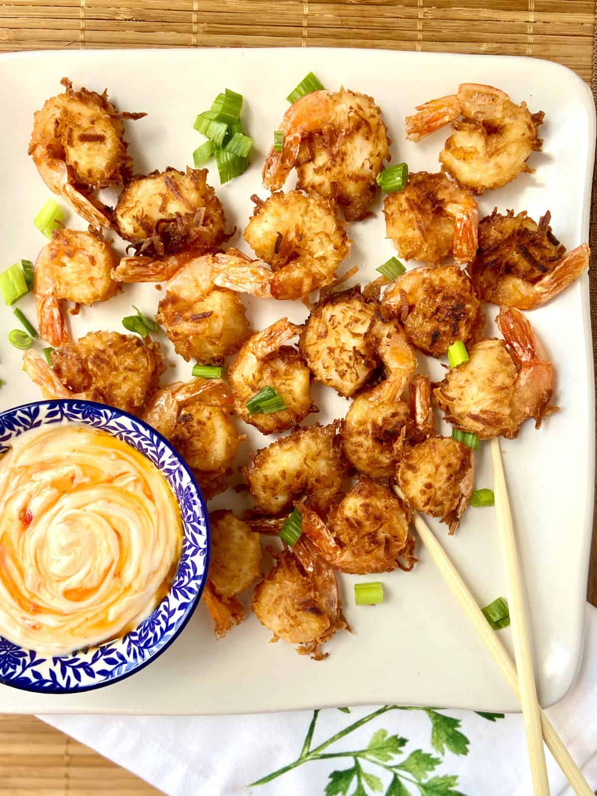 Coconut fried shrimp on white platter with dipping sauce.