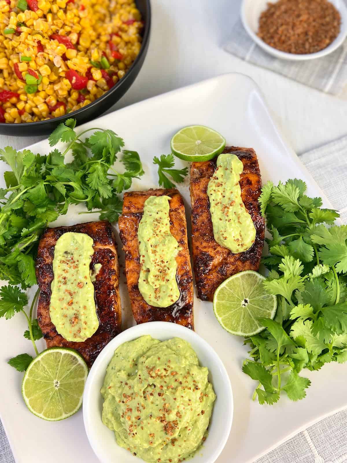 Three Tajin seasoned glazed salmon fillets with avocado cream.