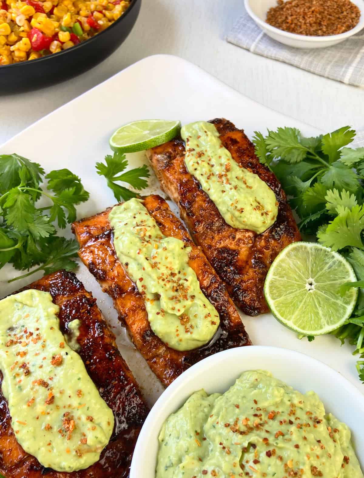 Three Tajin seasoned salmon fillets with avocado cream on top.