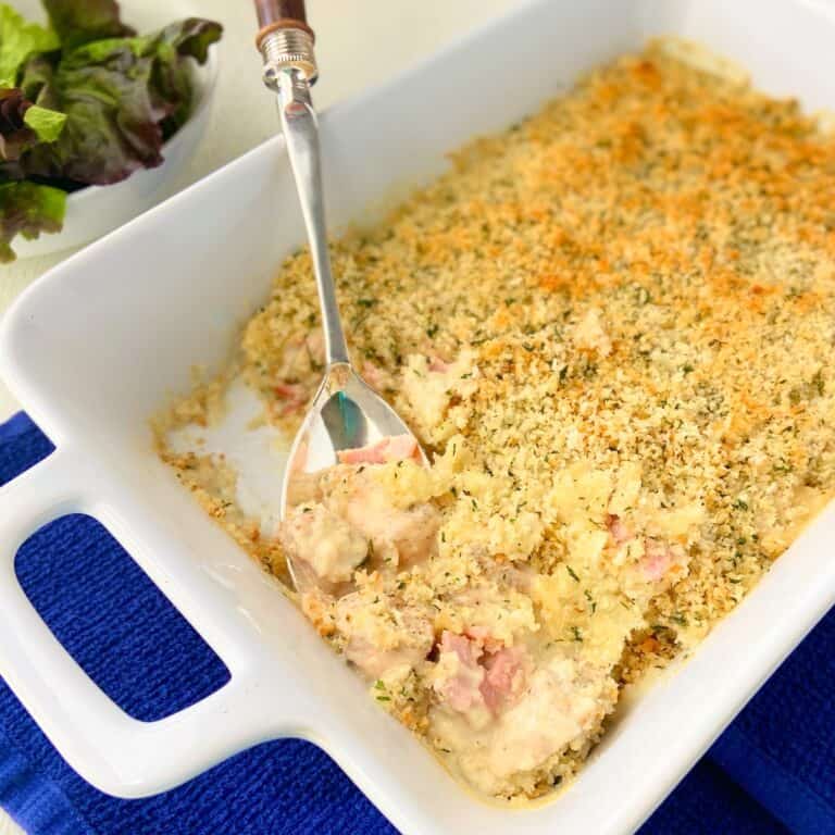 Cordon bleu casserole in white dish with serving spoon.