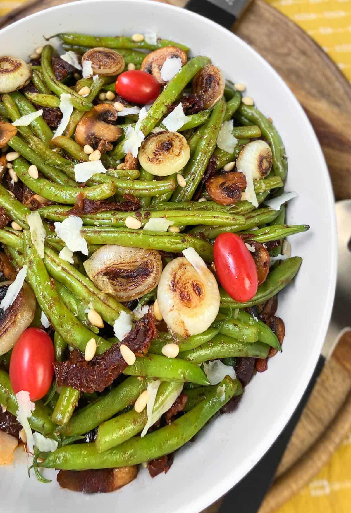 Italian green beans and sun dried tomatoes in white serving bowl.