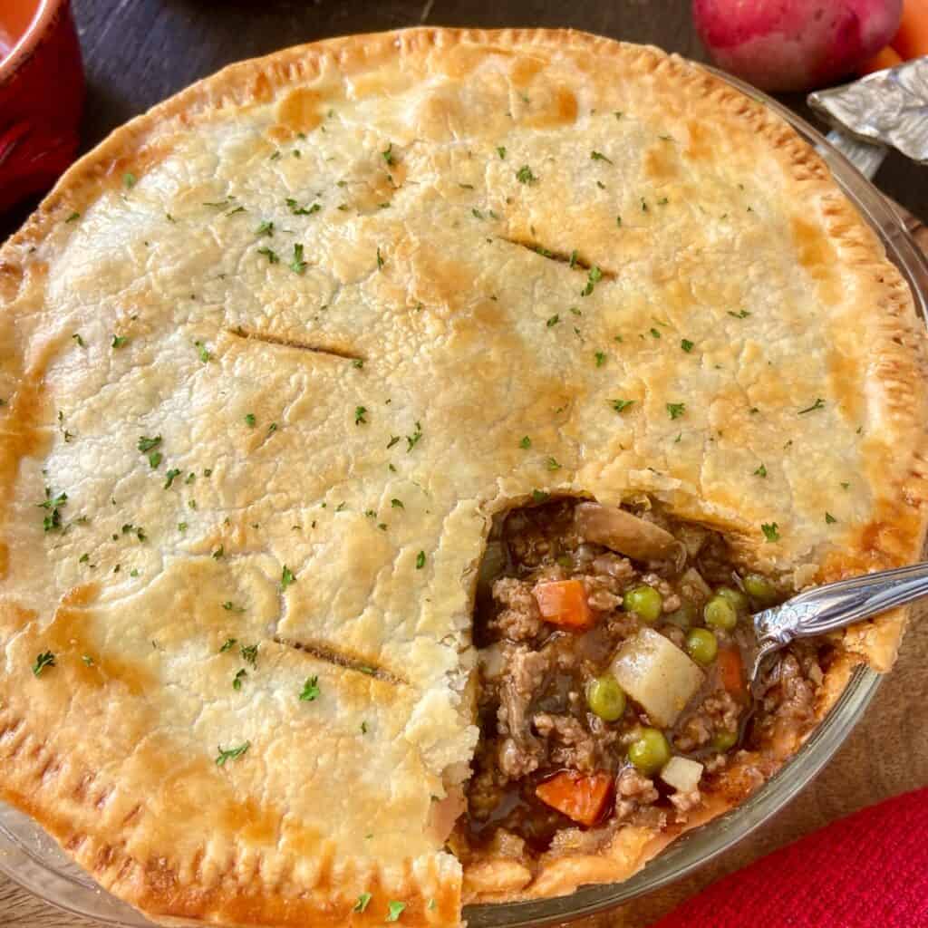 Ground beef pot pie crust and filling in pie plate.