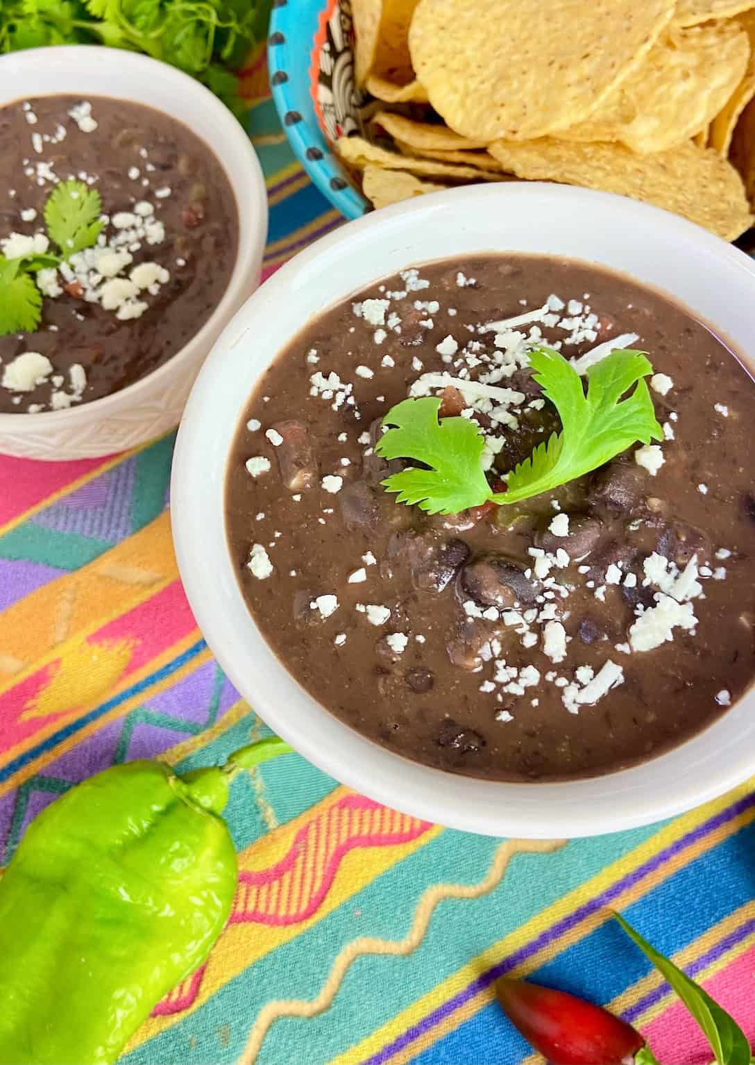Creamy Mexican black bean soup garnished with white cheese crumbles and cilantro.