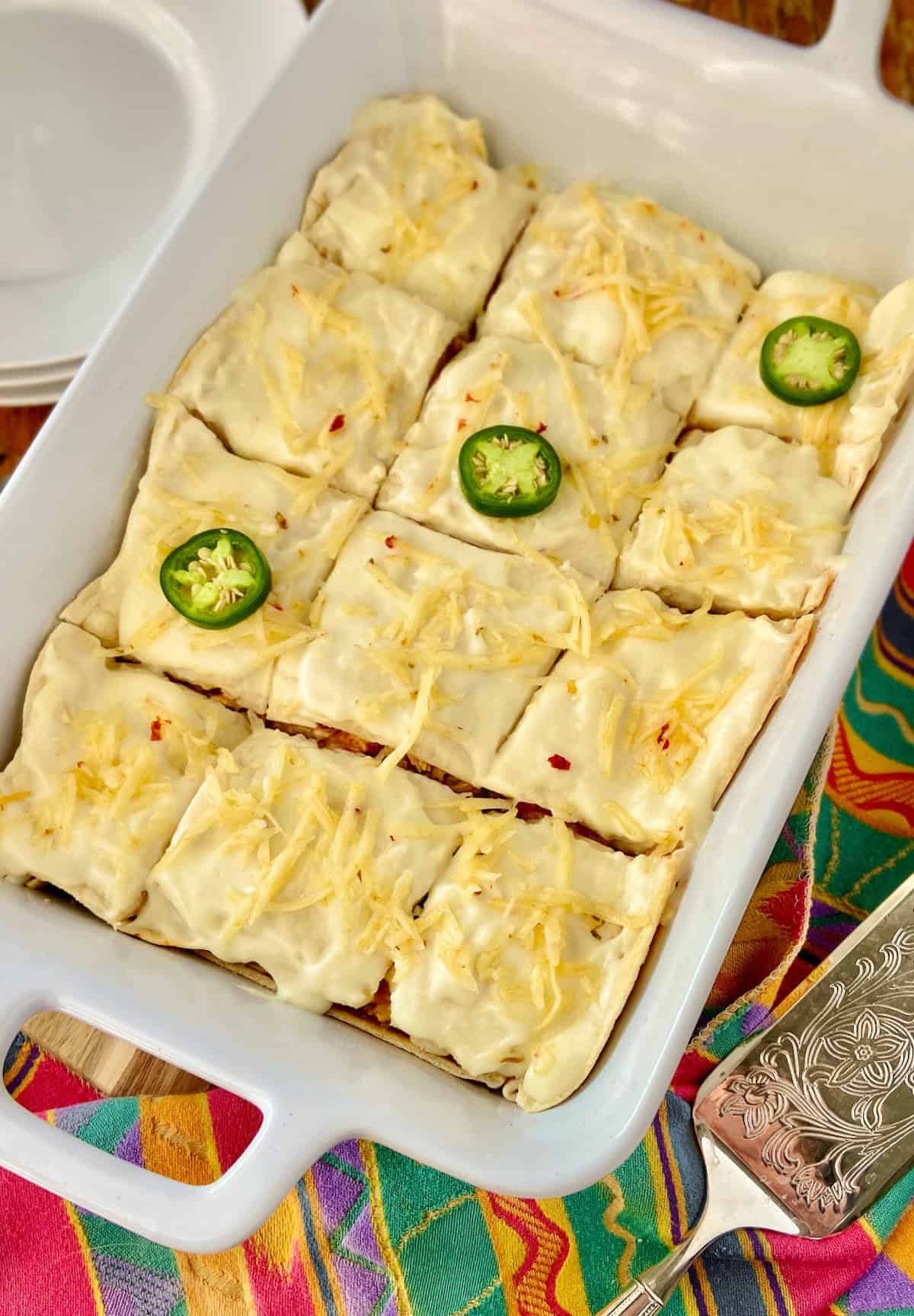 Sour Cream Enchilada Cassserole cut into twelve squares and garnished with fresh jalapeno slices.
