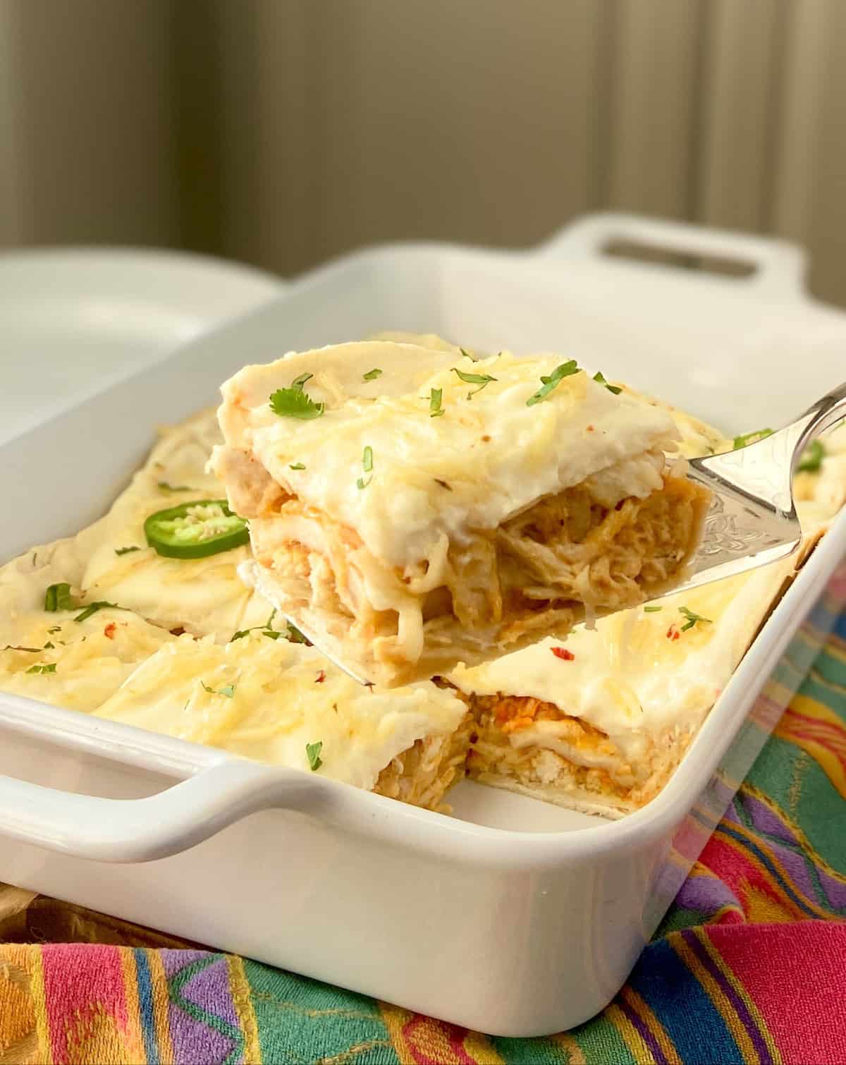 Slice of sour cream enchilada casserole on server.