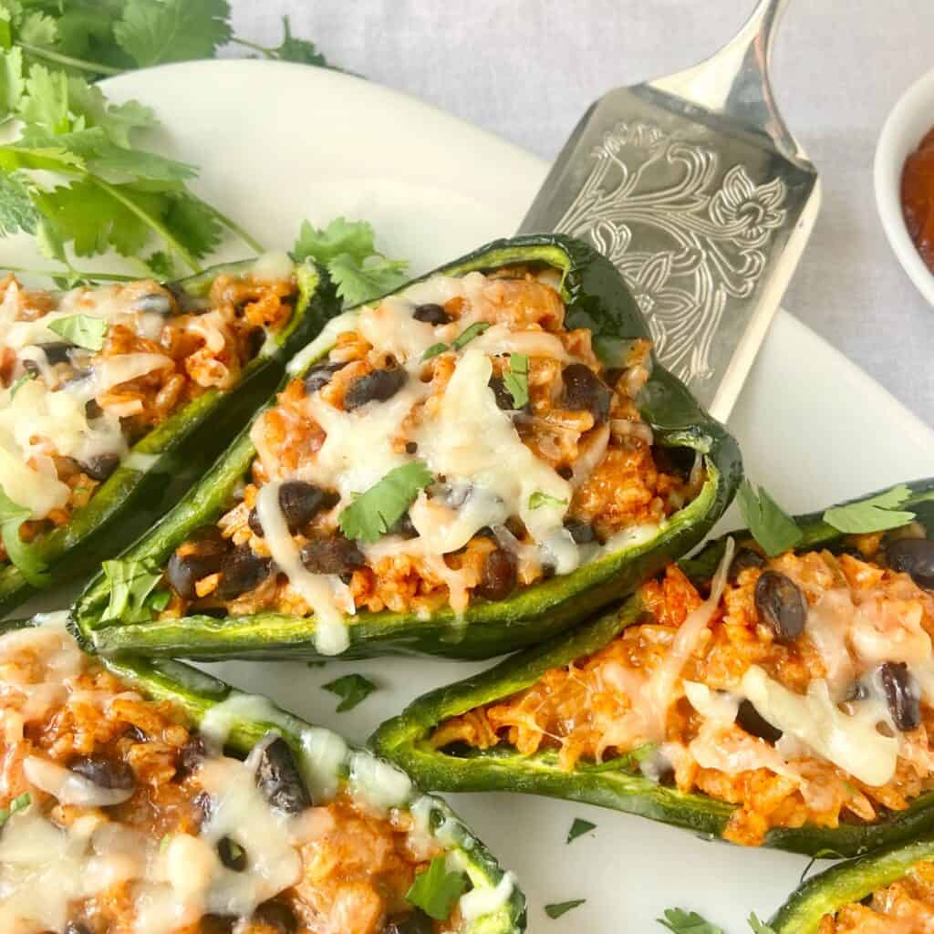 Stuffed poblano pepper on silver serving utensil.