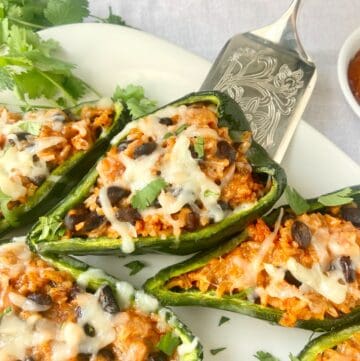 Stuffed poblano pepper on silver serving utensil.