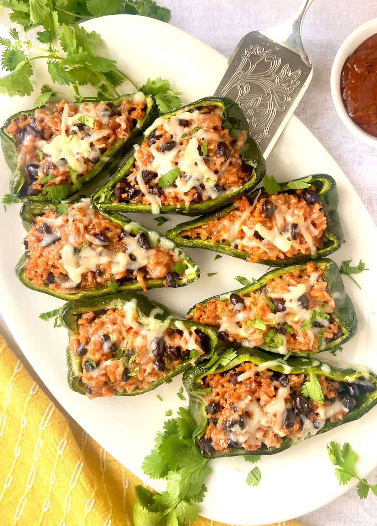 Platter of eight stuffed poblano peppers garnished with cilantro.