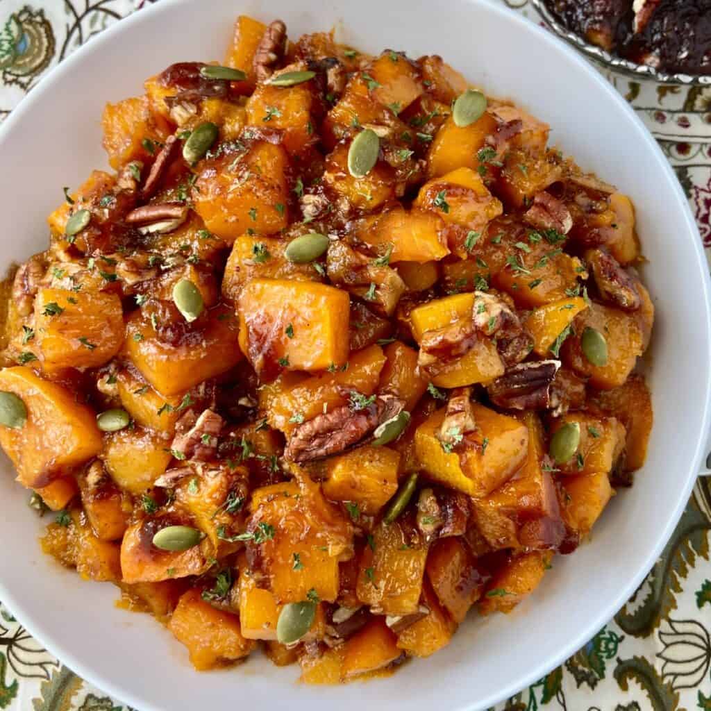 Roasted cubes of butternut squash in a white serving bowl.