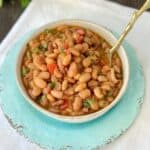 Charro beans in bowl garnished with chopped cilantro.