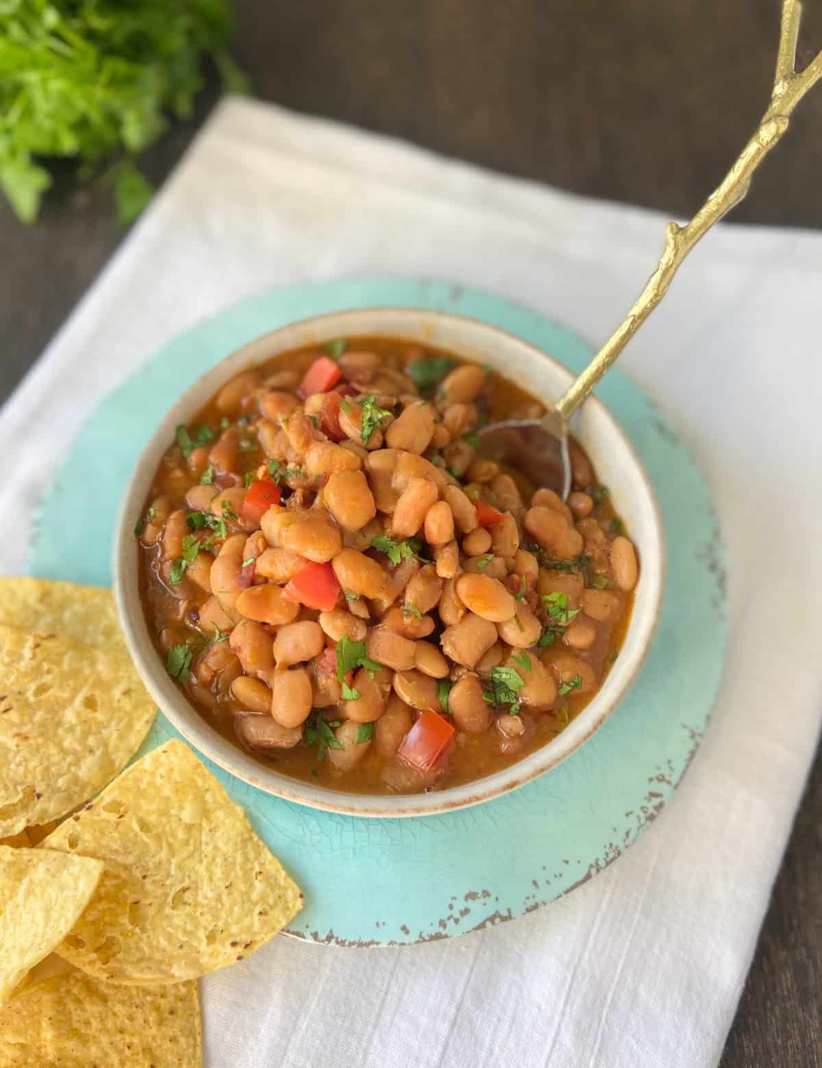Charro beans served with tortilla chips on the side.