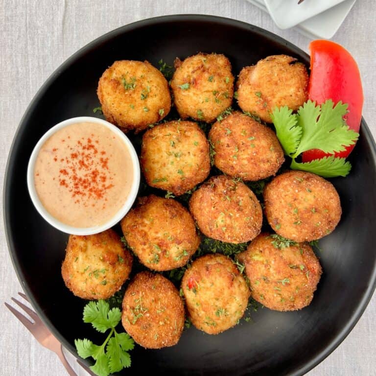 Golden fried crab balls in black bowl.
