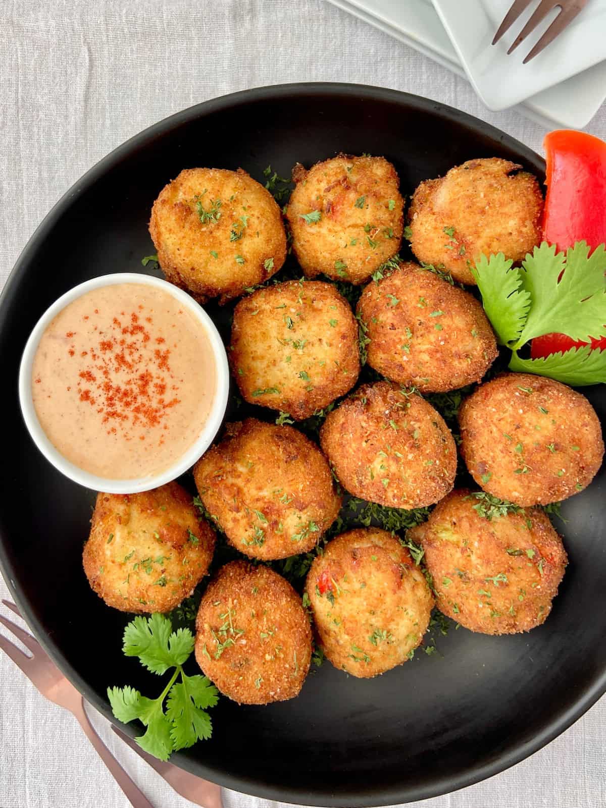 Golden fried crab balls in black bowl.