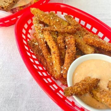Eggplant fries in red restaurant basket with dipping sauce.