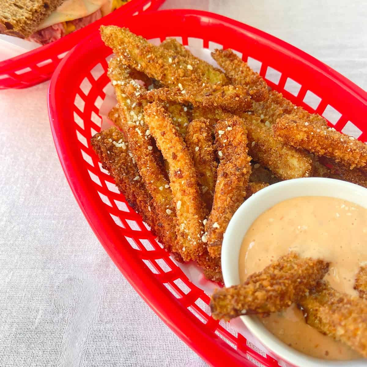 Eggplant fries in red restaurant basket with dipping sauce.