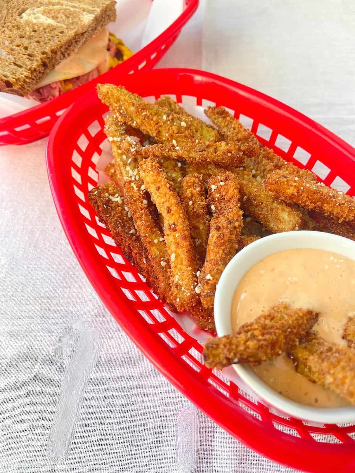 Crispy eggplant fries in a red diner basket with a dipping sauce.