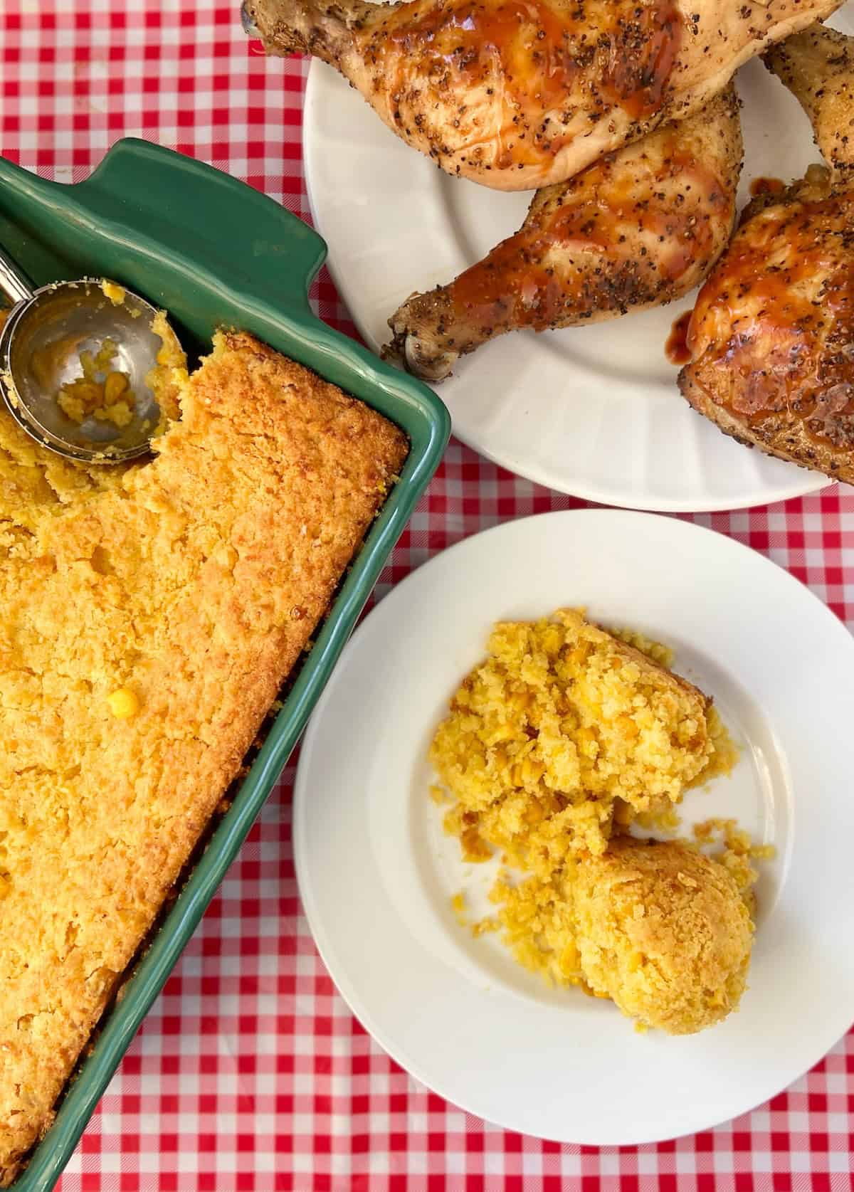 Sweet Mexican corn casserole in green dish with ice cream scoop.