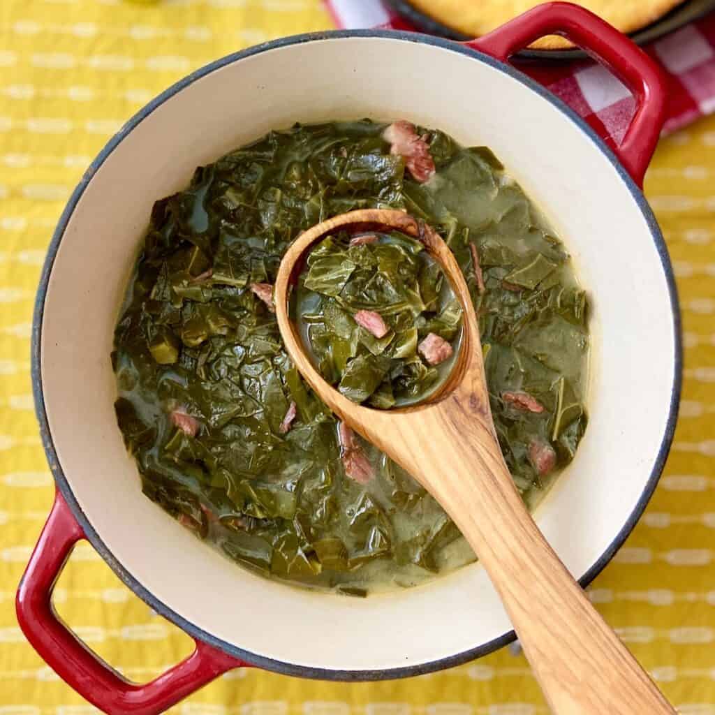 Stockpot with collard greens and a wooden ladle.