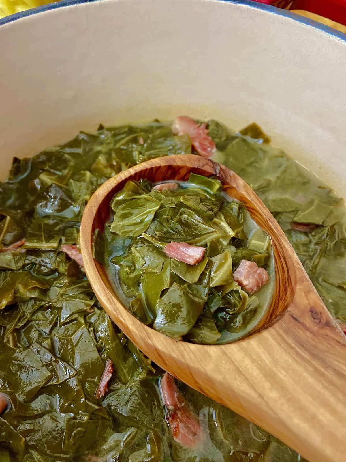 Collard greens in wooden ladle.