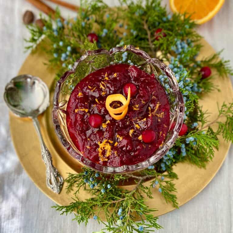Cranberry sauce in crystal bowl garnished with orange zest.
