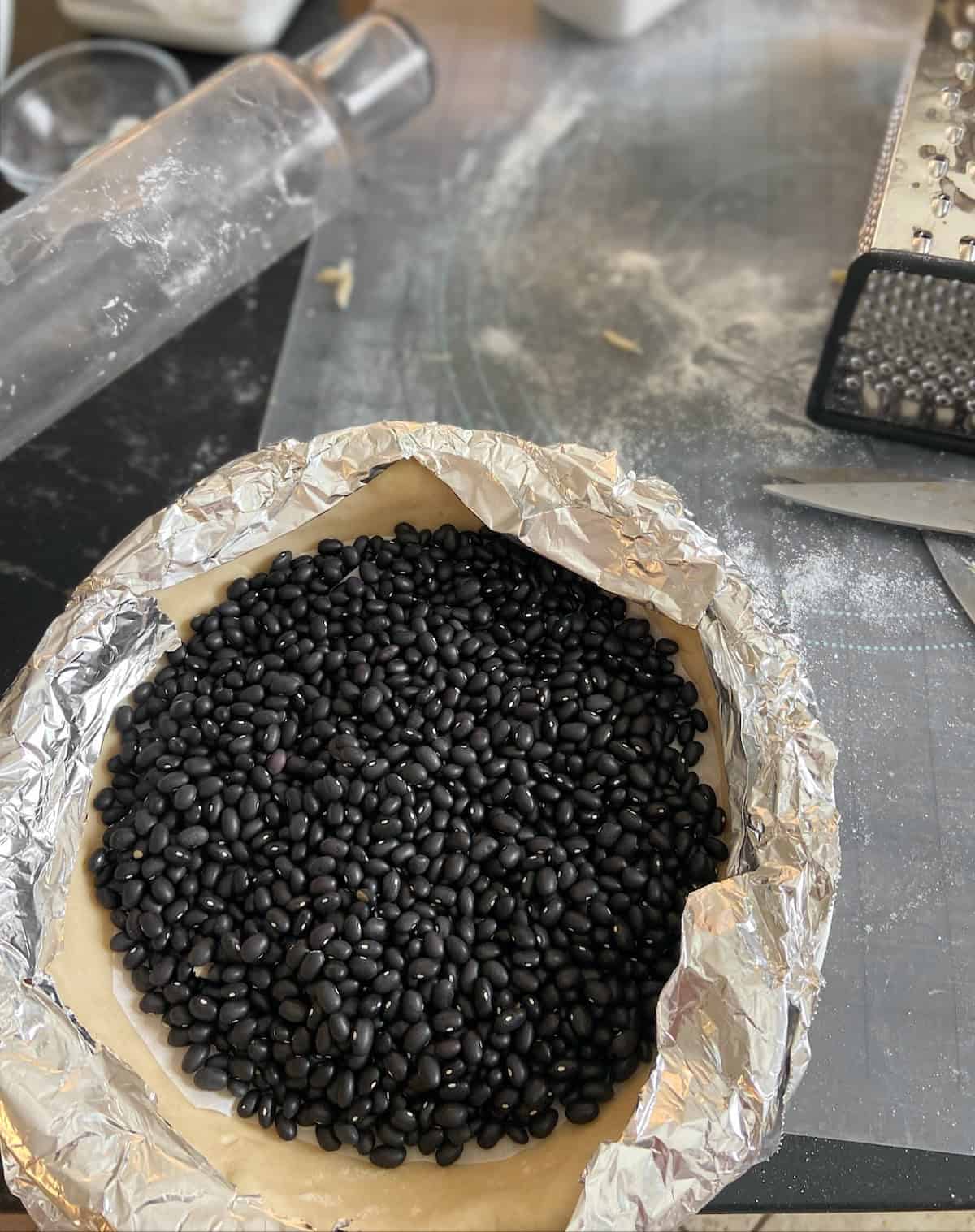 Dried black beans on raw pie crust lined with foil.