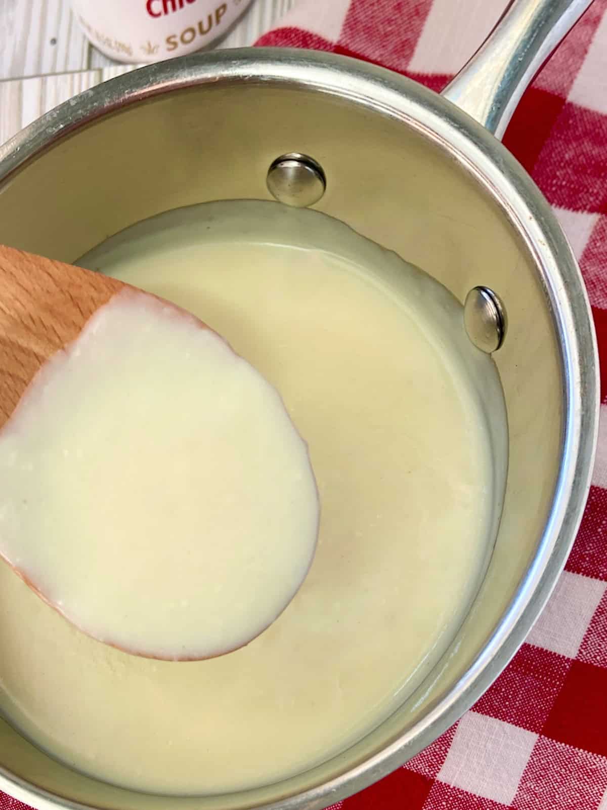 Condensed cream of chicken soup on wooden spoon.