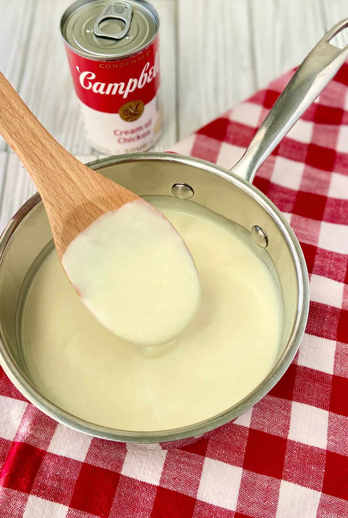 Condensed cream of chicken soup on wooden spoon.