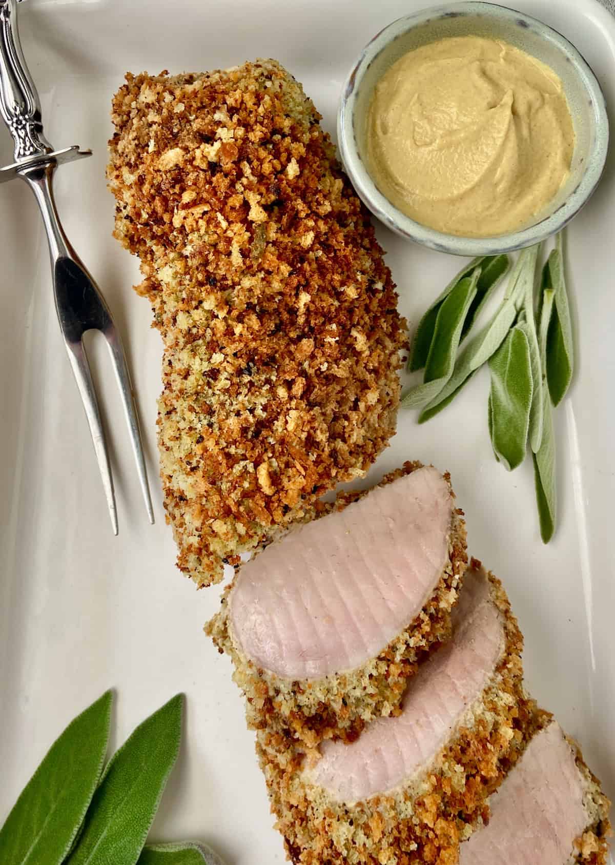 Panko crusted pork tenderloin on white platter.