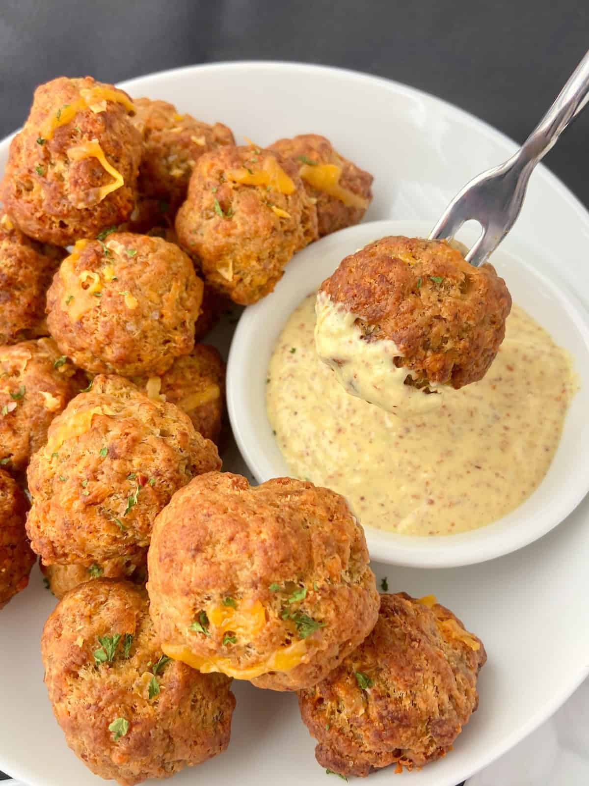 Sausage Balls on appetizer fork with mustard sauce.
