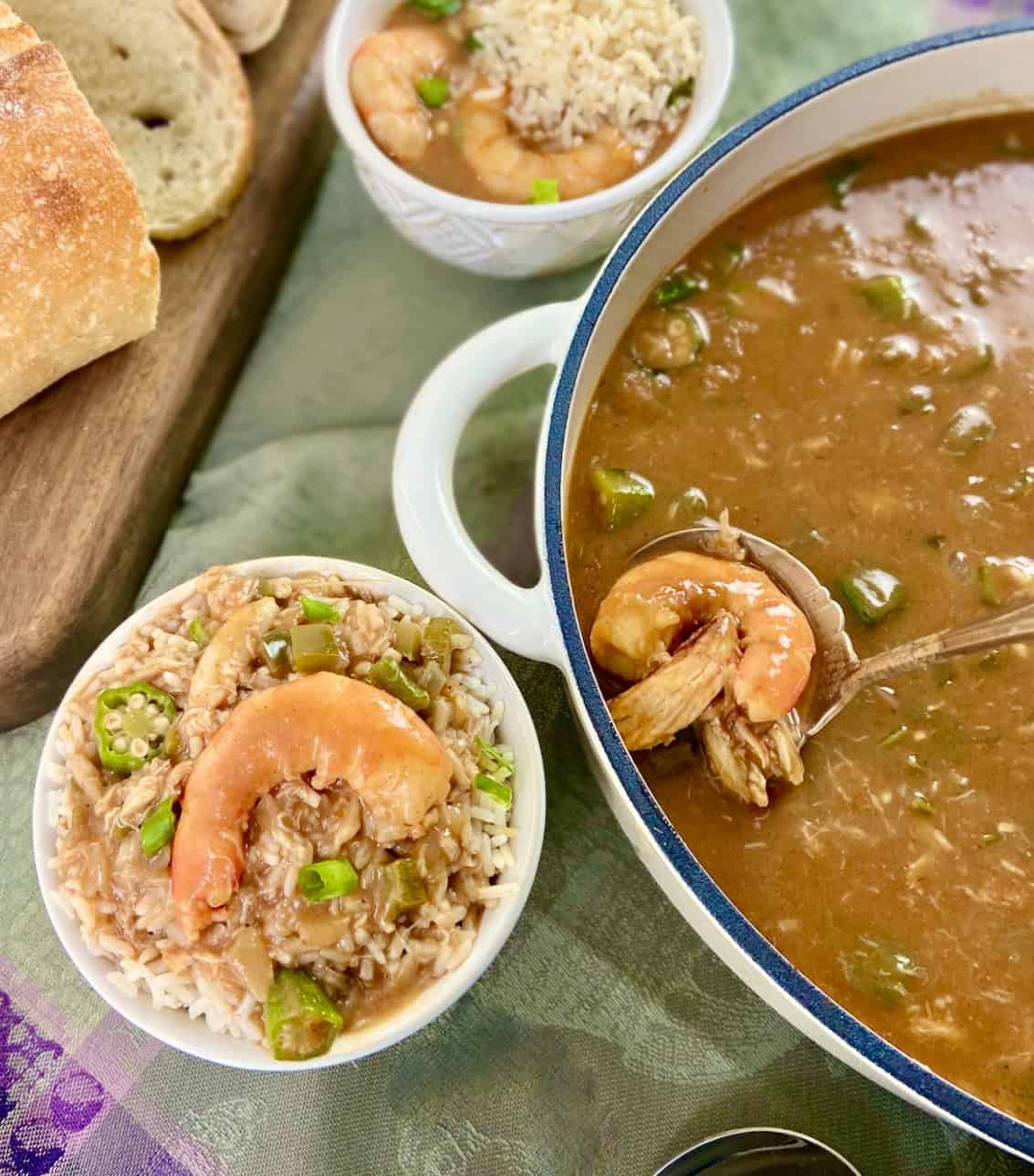 Seafood gumbo in stockpot next to a bowl of gumbo with rice.