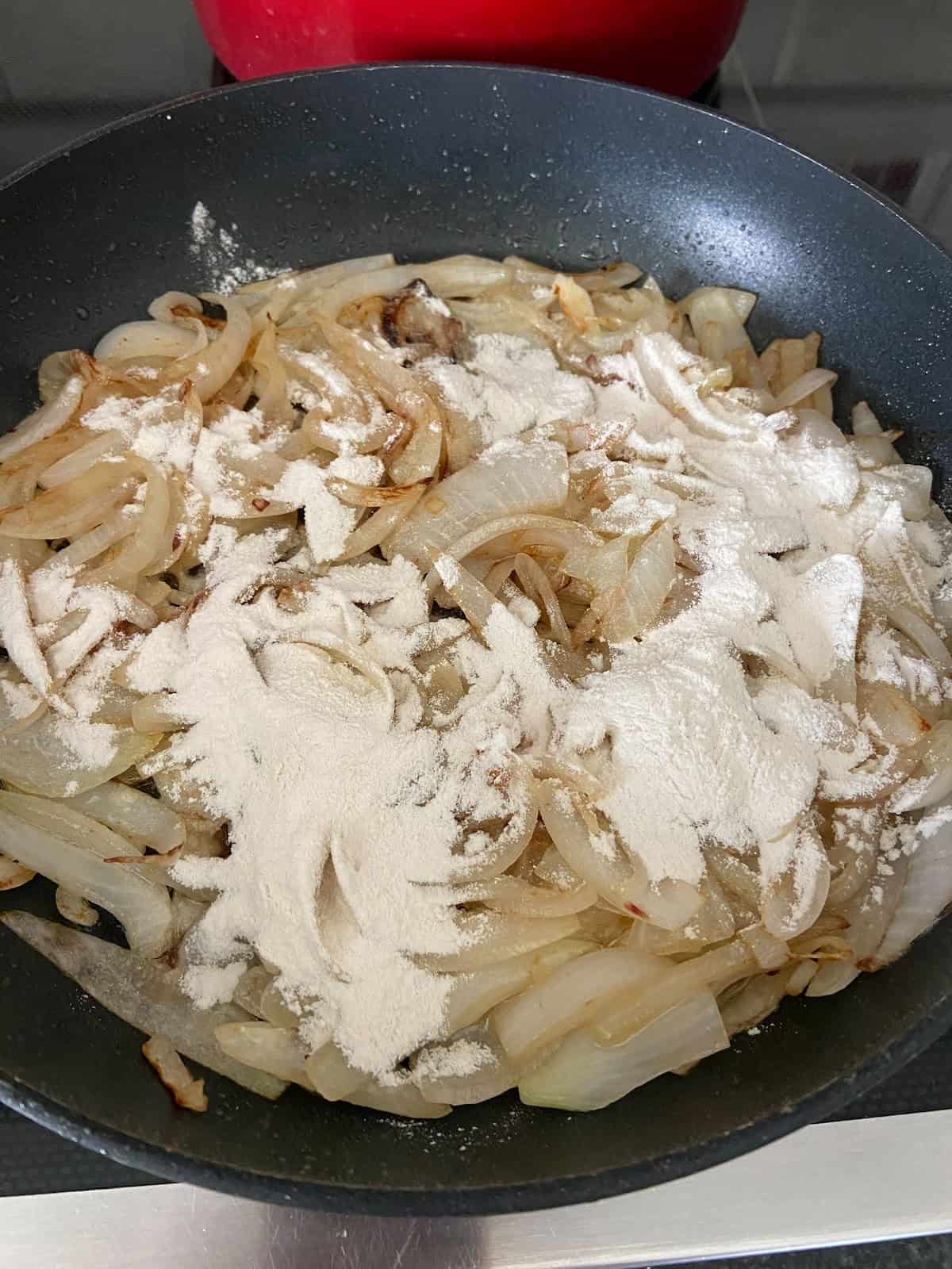 Add flour to cooked onions in skillet.
