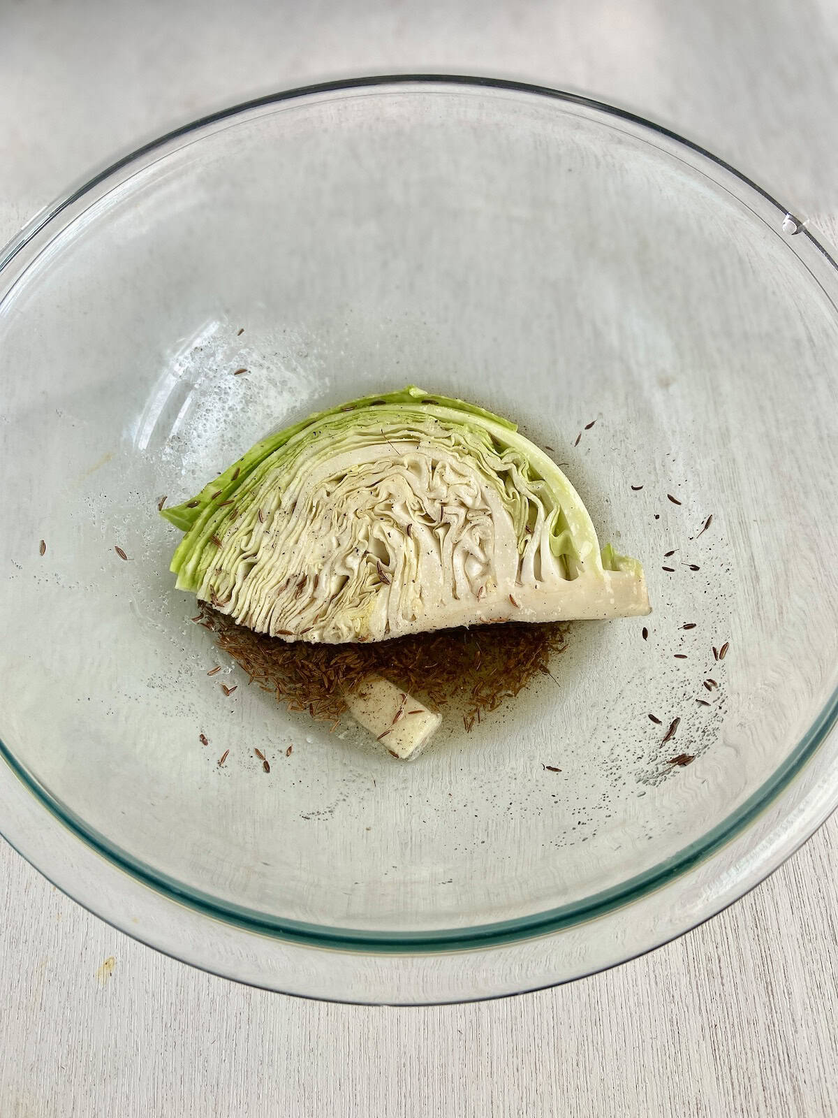Cabbage wedge in glass bowl with oil and seasonings.