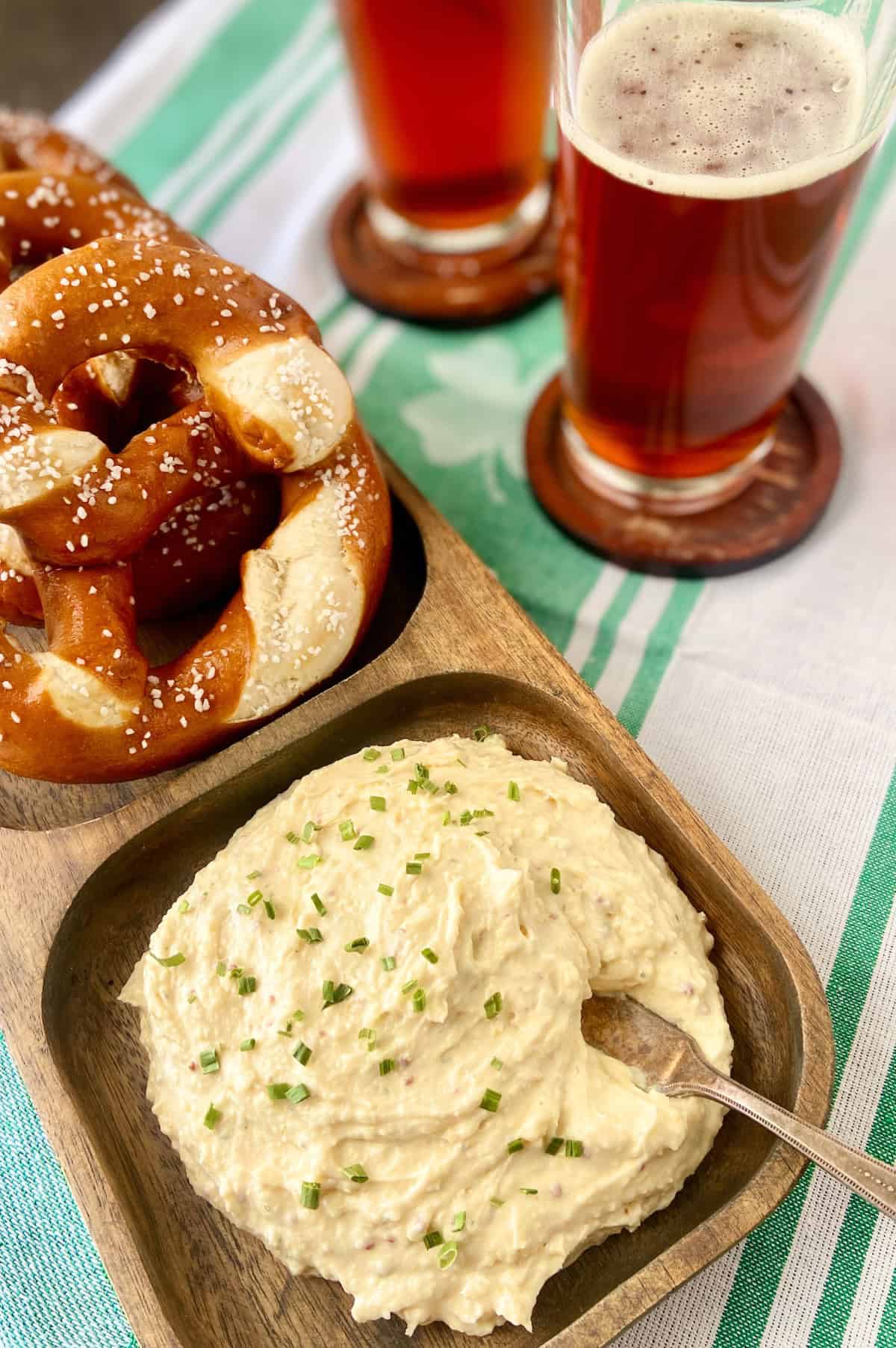 Irish Pub Cheese on wooden platter with knife spreader and salted pretzels.