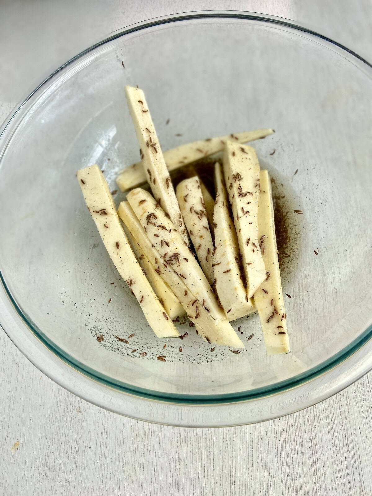 Sliced parsnips in glass bowl.