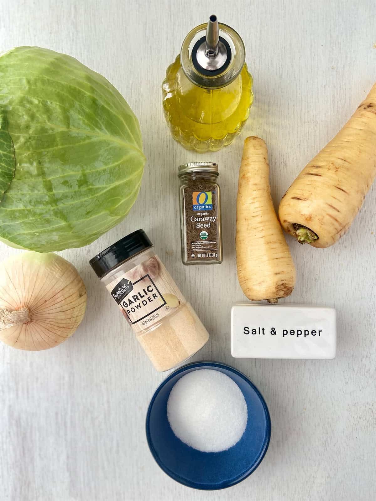 Ingredients for roasted cabbage wedges and parsnips on white wooden table.