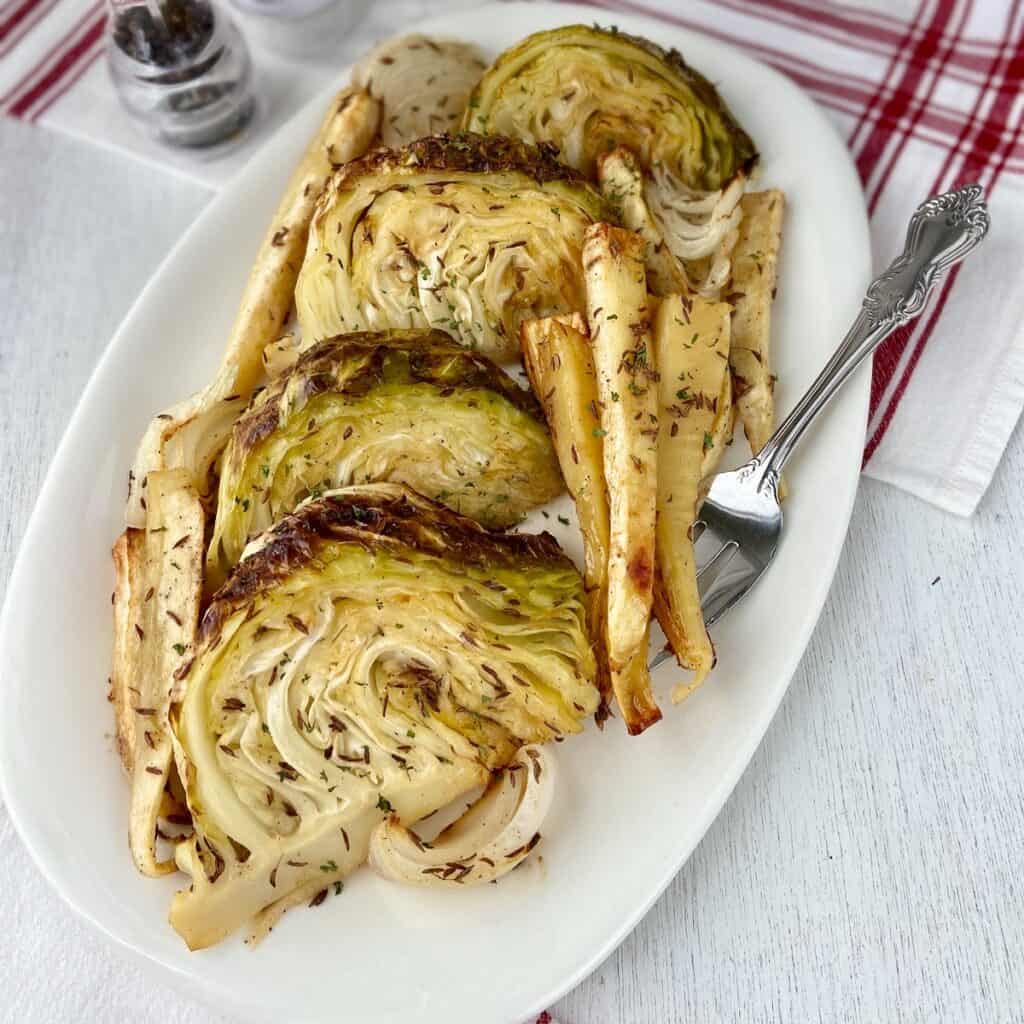 Roasted cabbage wedges and parsnips on white platter.