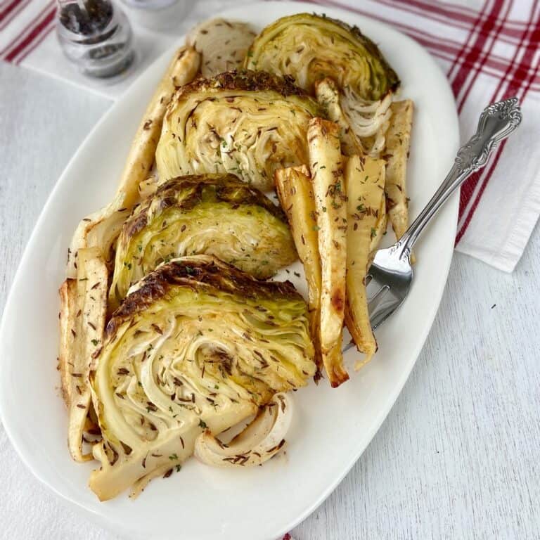 Roasted cabbage wedges and parsnips on white platter.
