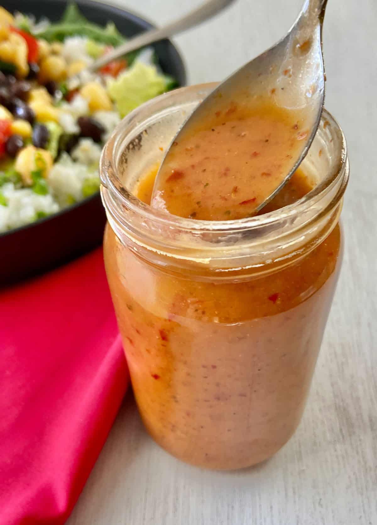 Chipotle Honey Vinaigrette in glass jar on spoon.